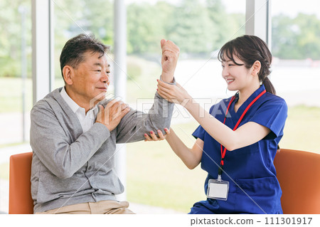 A female physical therapist/nurse (hand therapy/occupational therapist) giving rehabilitation guidance to an elderly man 111301917