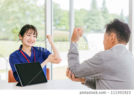 A female nurse/physiotherapist listens to an elderly male patient's elbow pain consultation A female nurse/physiotherapist listens to an elderly male patient's elbow pain consultation 111301923