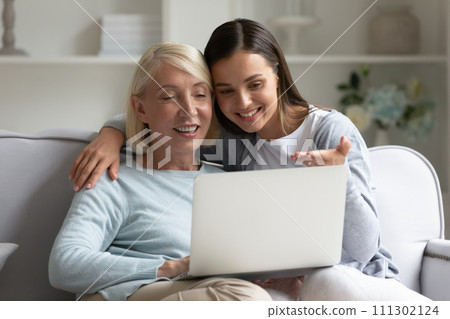 Happy mature mother and adult daughter using laptop, surfing internet Happy mature mother and adult daughter using laptop, surfing internet 111302124