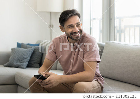 Cheerful middle aged man using mobile phone at home Cheerful middle aged man using mobile phone at home 111302125