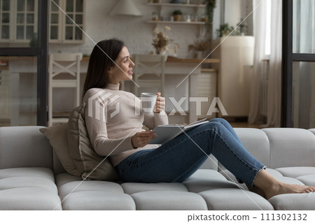 Peaceful woman relaxing on couch drink tea reading a book 111302132