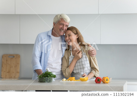 Happy old father hugging pretty young adult daughter in kitchen 111302194