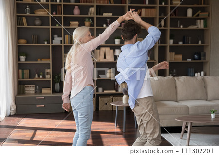 Older woman dance with young adult son at home Older woman dance with young adult son at home 111302201