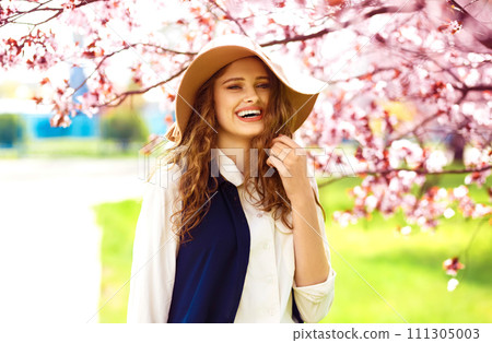 Outdoor portrait of young beautiful fashionable lady posing near flowering tree. 111305003