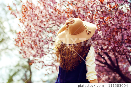 Outdoor portrait of young beautiful fashionable lady posing near flowering tree. 111305004