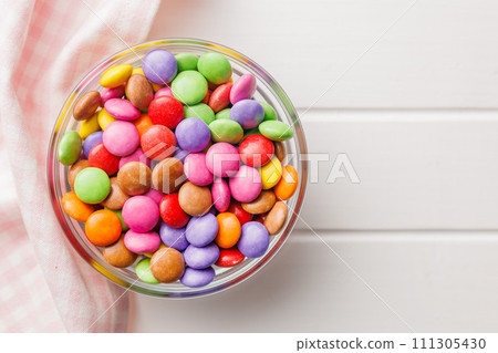 Colorful sweet candies in bowl on white table. Top view. 111305430