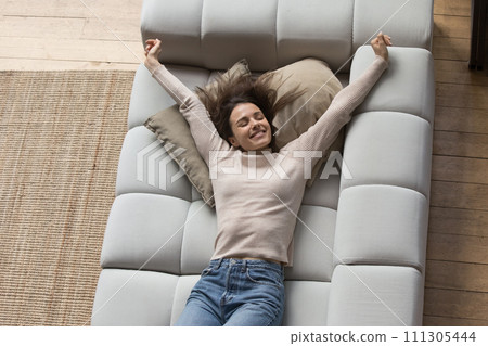 Well rested woman stretching lying on cozy sofa, top view 111305444