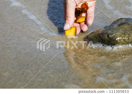 Beautiful pieces of amber in the hand of the sea background. A glowing wavy piece of amber in the palm of your hand. The sunstone. 111305653