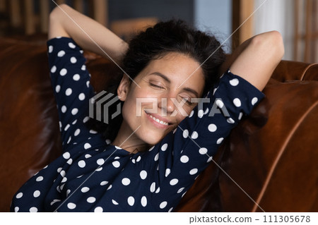Close up smiling relaxed woman leaning back on cozy couch 111305678