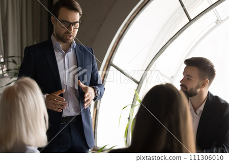 Serious confident company director man talking to employees on meeting 111306010