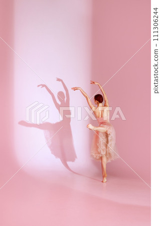 Ethereal Ballet. Classic ballerina dances barefoot in pink traditional ballet dress, tutu against background with her shadow. Ethereal Ballet. Classic ballerina dances barefoot in pink traditional ballet dress, tutu against background with her shadow. 111306244