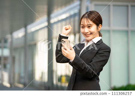 Young woman business smartphone fist pump 111306257
