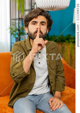 Middle eastern man presses finger to lips makes silence hush sign do not tells gossip secret, quiet Middle eastern man presses finger to lips makes silence hush sign do not tells gossip secret, quiet 111306516