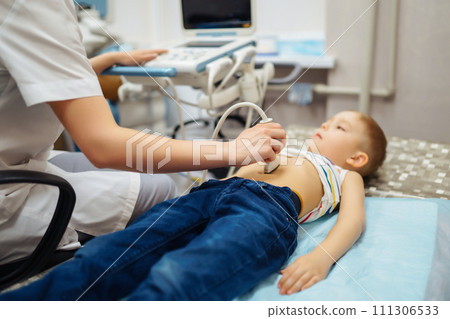 Boy undergoing thyroid ultrasound examination. Doctor examining kid throat in clinic with equipment. 111306533