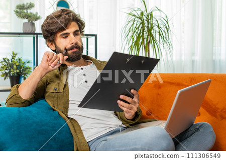 Young man freelancer work with documents from home, analyzing information prepare financial report 111306549