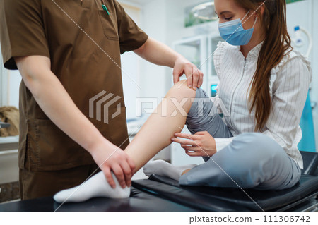 Patient visit doctor after suffering leg injury Doctor examines patient, examines picture of patient Patient visit doctor after suffering leg injury Doctor examines patient, examines picture of patient 111306742