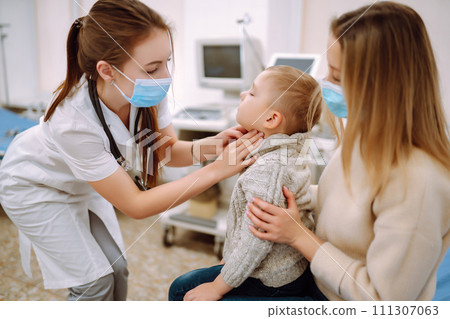 Pediatrician examines sick boy. Child with his mother in office of pediatrician or otolaryngologist. Pediatrician examines sick boy. Child with his mother in office of pediatrician or otolaryngologist. 111307063