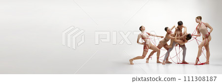 Male and female ballet dancers connected with red springs against white studio background. Support and assistance Male and female ballet dancers connected with red springs against white studio background. Support and assistance 111308187