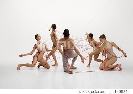 Social connections and freedom. Man and girl, ballet dancers connected with red strings, performing against white studio background 111308243