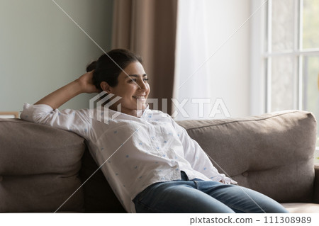 Young single 30s attractive Indian woman relaxing on comfortable sofa Young single 30s attractive Indian woman relaxing on comfortable sofa 111308989