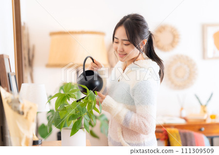 給室內植物澆水的大學女性 111309509