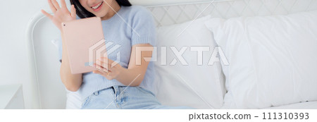 Happiness young asian woman sitting on bed video call with digital tablet in the bedroom. Happiness young asian woman sitting on bed video call with digital tablet in the bedroom. 111310393