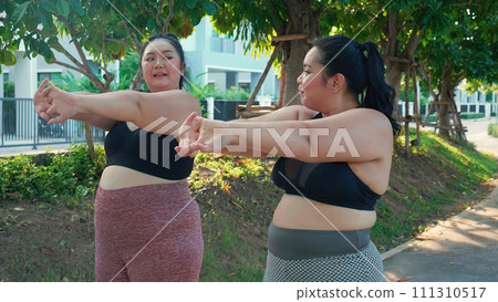Obese two young asian woman doing stretching arm muscle in the park. Obese two young asian woman doing stretching arm muscle in the park. 111310517