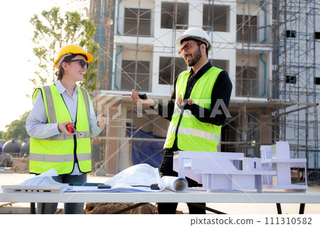 Team architect and builder talking and holding model house at construction site. Team architect and builder talking and holding model house at construction site. 111310582