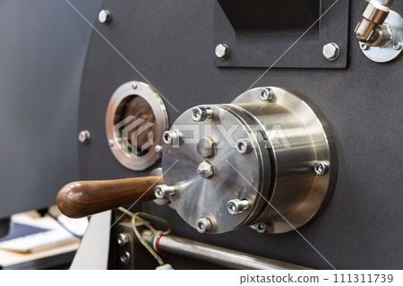 Industrial coffee roaster close-up photo, roasting coffee seeds are inside Industrial coffee roaster close-up photo, roasting coffee seeds are inside 111311739