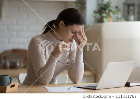 Young woman feels overworked takes off glasses relieving eye strain 111311762