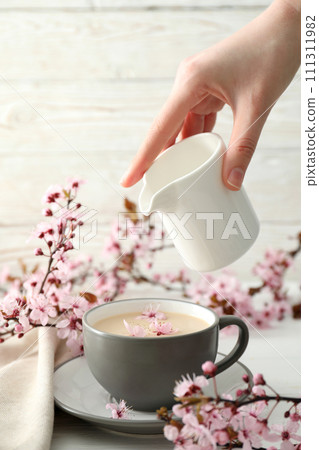 Spring twigs with flowers with a cup of hot drink, on a light wooden background. Spring twigs with flowers with a cup of hot drink, on a light wooden background. 111311982
