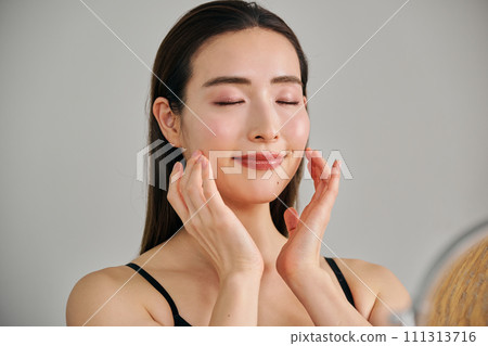 30多歲的女人透過按摩臉部來護理皮膚 30多歲的女人透過按摩臉部來護理皮膚 111313716