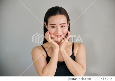 A woman in her 30s taking care of her skin by massaging her face A woman in her 30s taking care of her skin by massaging her face 111313726