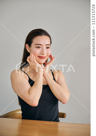 A woman in her 30s taking care of her skin by massaging her face 111313728