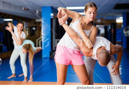 Young woman practicing self defence techniques with coach 111314019