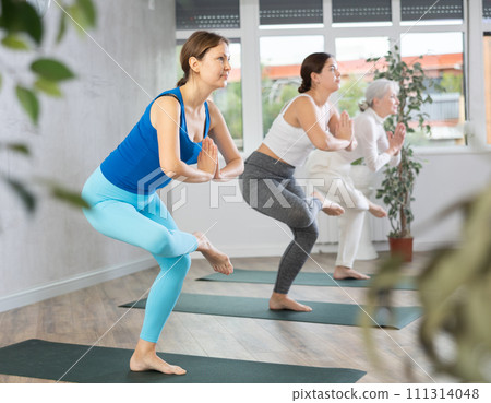 Group of women practice the eagle pose Group of women practice the eagle pose 111314048