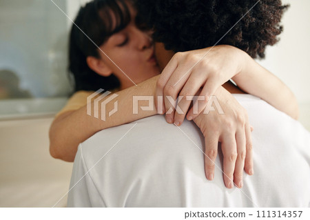 Hands of young affectionate woman with closed eyes embracing her husband by neck and kissing him in front of camera 111314357