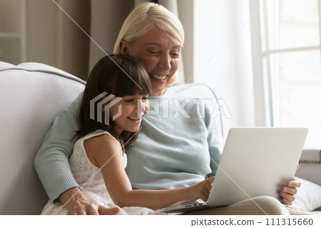 Happy grandmother and granddaughter having fun with laptop together 111315660