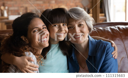 Portrait mature grandmother adult mother preteen daughter cuddle on couch 111315683