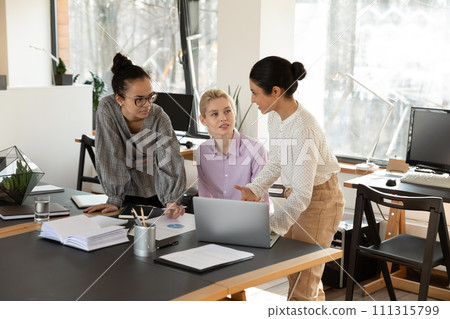 Multiracial female colleagues work together using laptop Multiracial female colleagues work together using laptop 111315799