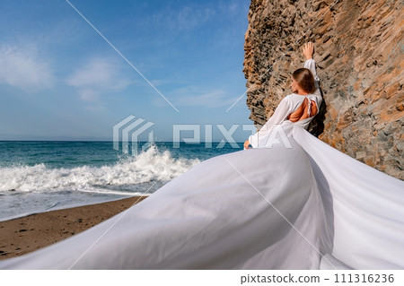Woman beach white dress flying on Wind. Summer Vacation. A happy woman takes vacation photos to send to friends. 111316236