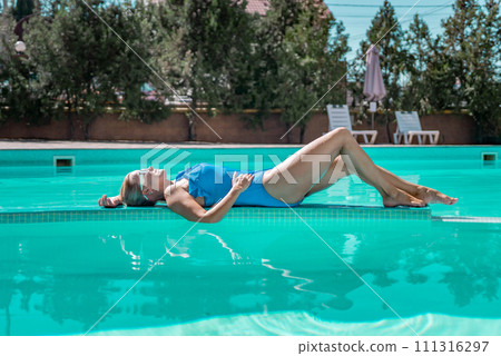 Bikini-clad woman enjoys poolside relaxation. Poolside ambiance. Capturing woman's relaxed time near pool. 111316297