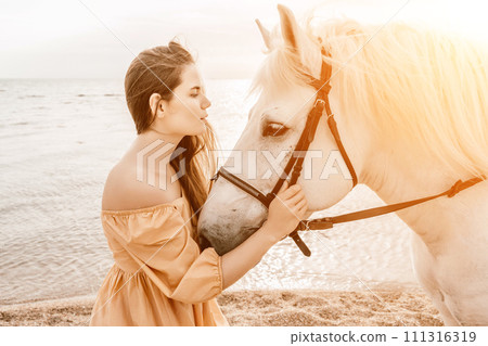 A woman in a dress stands next to a white horse on a beach, with the blue sky and sea in the background. A woman in a dress stands next to a white horse on a beach, with the blue sky and sea in the background. 111316319