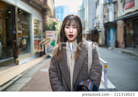 A young woman with long hair wearing a coat taking a walk A young woman with long hair wearing a coat taking a walk 111318023
