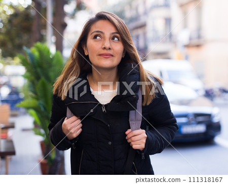 Positive latin american girl walking along city street 111318167