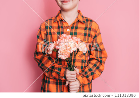 Boy in checkered shirt and with bouquet of flowers congratulates on the holiday against pink background 111318396