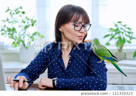 Close-up of green parrot on the shoulder of a female owner 111320323