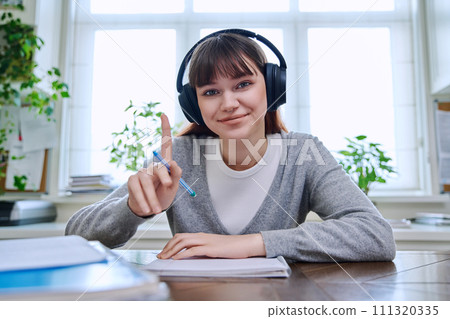 Web camera view of teenage student girl in headphones looking at camera 111320335