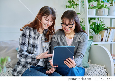 Happy mother and teenage daughter looking together at screen of digital tablet Happy mother and teenage daughter looking together at screen of digital tablet 111320368