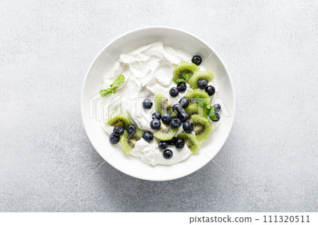 White plain greek yogurt with fresh blueberries and kiwi fruit, top view 111320511
